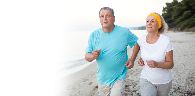 A man and woman jogging on the beach.